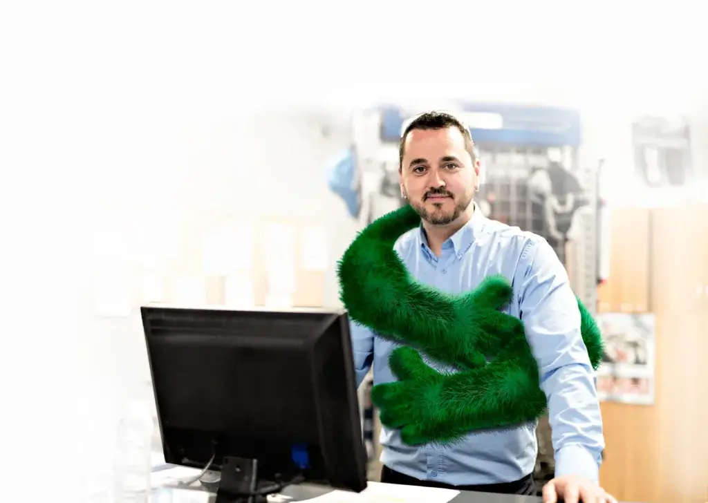 A man stands beside a computer monitor